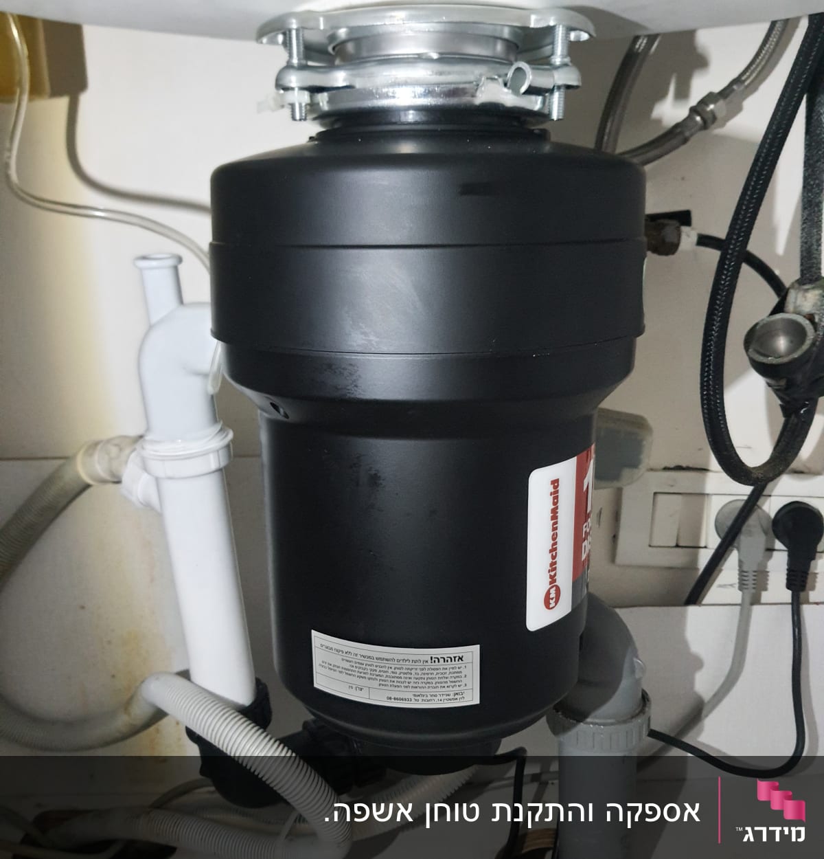 מכשיר טוחן אשפה מותקן מתחת לכיור עם צינורות חיבור